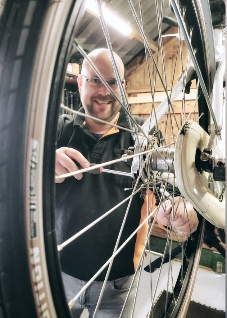 Ben Elsinga stelt de spaken van een fietswiel af in zijn werkplaats in Niezijl